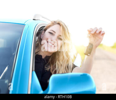 Young attractive happy woman shows keys from the new car. Stock Photo