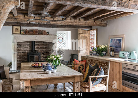 Beamed kitchen with stainless steel LED lights designed by Mirka McNeill and 18th century French limestone fireplace  and artwork by Jeremy Barlow Stock Photo