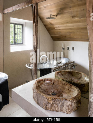 Bathroom with mirrored wall bisecting reclaimed beams sourced in Indonesia with Italian marble floor and walls Stock Photo