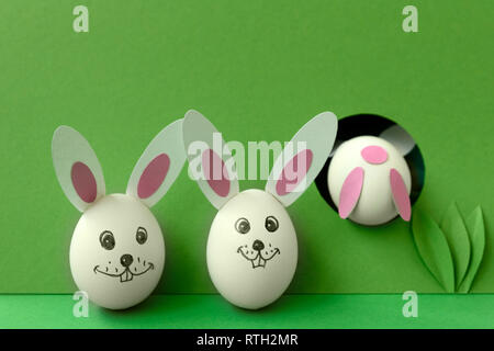Easter bunny made from eggs and paper ears jump in hole on green pastel background. Creative idea. Art food concept. Stock Photo