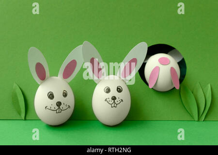 Easter bunny made from eggs and paper ears jump in hole on green pastel background. Creative idea. Art food concept. Stock Photo