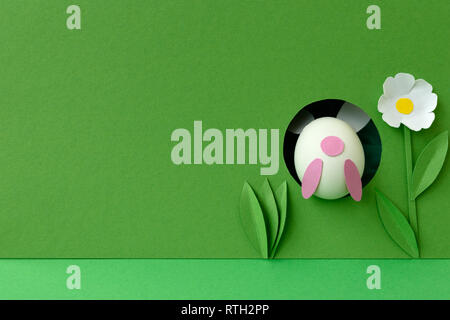 Easter bunny made from eggs and paper ears jump in hole on green pastel background. Creative idea. Art food concept. Stock Photo
