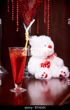Strawberry cocktail with ice cubes on a blurred background white teddy bear. Stock Photo