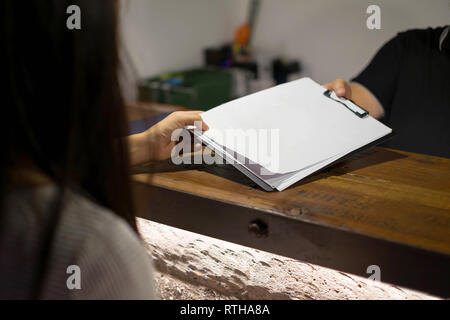 Receptionist's sent the documents to guest for signing and filling up form check-in process.Hotel concept. Stock Photo