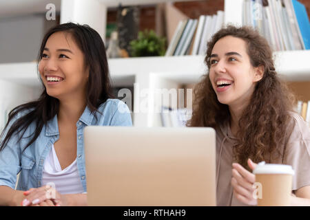 Diverse happy girls students looking away smiling listening to lecture Stock Photo