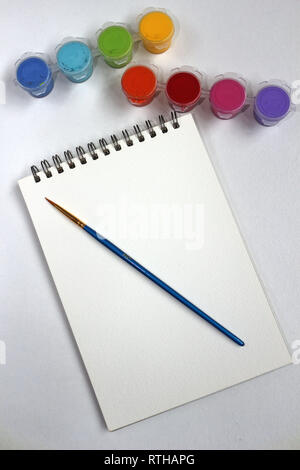 A blank pad of paper with paints and a paint brush Stock Photo