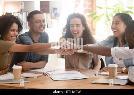 Happy multiracial business people colleagues stacking hands motivated by success Stock Photo