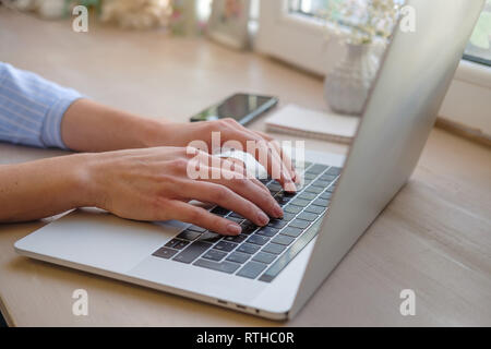 Working at home with laptop woman writing a blog. Female hands on the keyboard. Close up Stock Photo