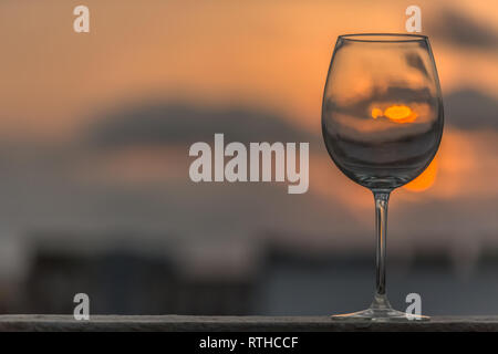 View of a amazing empty glass of wine standing tall, sunset as background ... Stock Photo