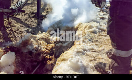 Spilled oil on sandy soil near pipelines and process equipment. Oil leaks during operation and repair Stock Photo