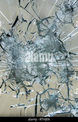A heavily damaged window pane with large shards and cracks. Maybe even shot on it and it consists of the bulletproof glass Stock Photo