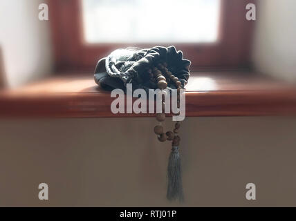 Tulasi wooden rosary beads lie on a rock background in the green grass. Japa mala. Mantra. 108 beads.