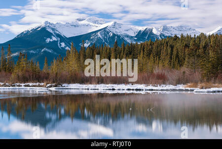 Sunrise at Vermilion Lakes near Banff, Alberta, Canada with the surrounding mountains reflected in the ice and water. Stock Photo