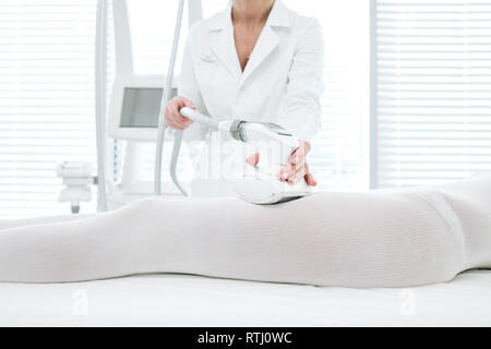LPG massage procedure for cellulite and fat reduction. Cropped woman in white body suit Getting Anti Cellulite massage on problem areas of the body, c Stock Photo
