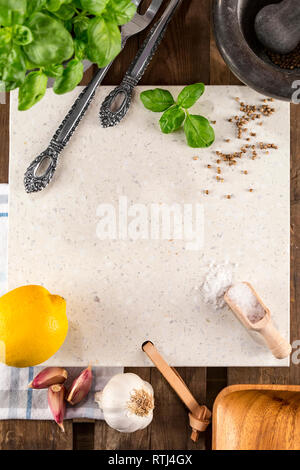 Concrete stone server with space for text on rustic wood planks. Arranged herbs, spices, garlic, lemon, cutlery, porcelain mortar and wooden scoop- Stock Photo