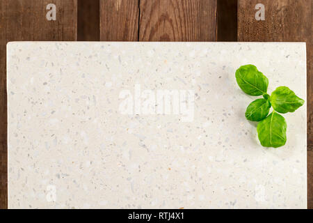 Concrete stone server with basil with space for text on rustic wood plank surface. Top view, flat lay, from above, overhead. Stock Photo