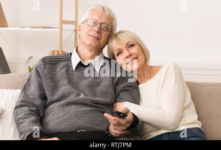 Loving senior couple watching tv with remote control Stock Photo