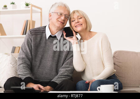 Senior couple sharing smartphone, having phone call Stock Photo