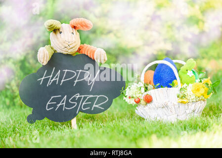Happy Easter text on blackboard and basket with Eastertide symbols Stock Photo