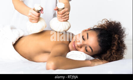 Woman having Thai herb compress massage in beauty spa Stock Photo