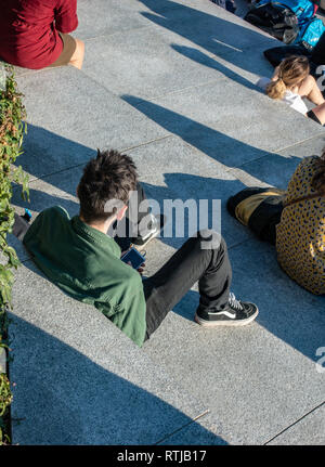 shot from above lone man sitting on steps relaxing with his mobile Stock Photo