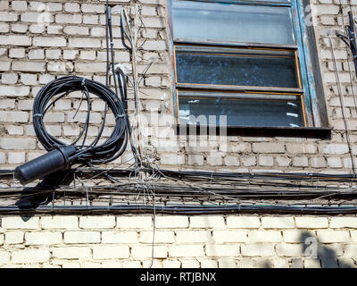 Communication cables on the brick wall of the house Stock Photo