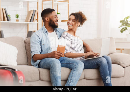 Planning tour. African-american couple using laptop at home
