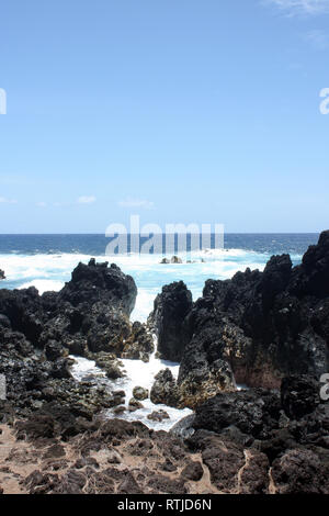 Large, jagged, black lava rock and boulders fronting the Pacific Ocean at Laupahoehoe Point in Hawaii, USA Stock Photo