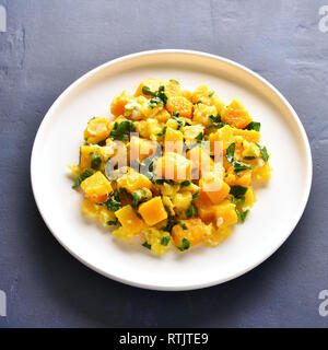Stir-fried pumpkin with eggs on plate over blue stone background. Pumpkin and egg stir fry in thai style. Stock Photo