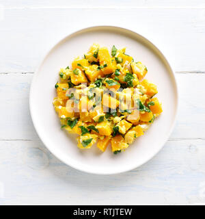 Stir-fried pumpkin with eggs on plate over white wooden background. Pumpkin and egg stir fry in thai style. Top view, flat lay Stock Photo
