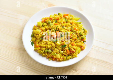 Healthy vegetarian pilaf on white plate over wooden background. Stock Photo