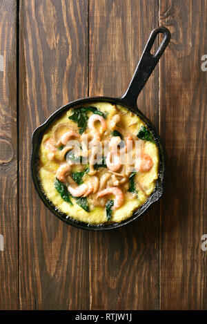 Mushroom and spinach frittata with shrimps in frying pan on wooden background with copy space. Top view, flat lay Stock Photo