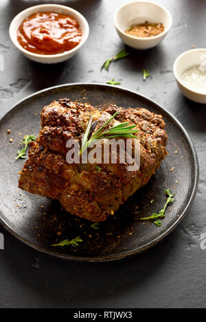 Barbecue meat. Grilled beef on plate over black stone table Stock Photo