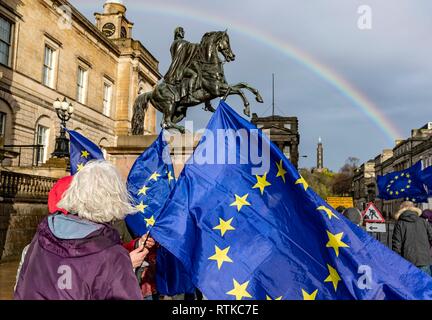 Edinburgh. UK. 2nd March 2019. Anti-Brexit Protesters gather below the statue of the Duke of Wellington on Edinburgh's Princes Street as a rainbow reaches over the Nelson monument on Calton Hill Credit: Rich Dyson/Alamy Live News Stock Photo