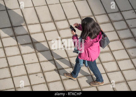 Woman looking at cell phone while walking, Portland, Oregon. Stock Photo