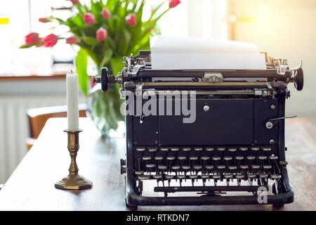 the old typewriter standing on the table near the window Stock Photo