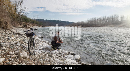 Man with mountain bike on the river. Ticino river, Italy Stock Photo