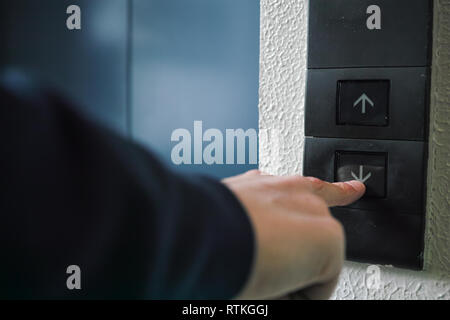 A rear view of a man pushing an elevator button with his index finger Stock Photo