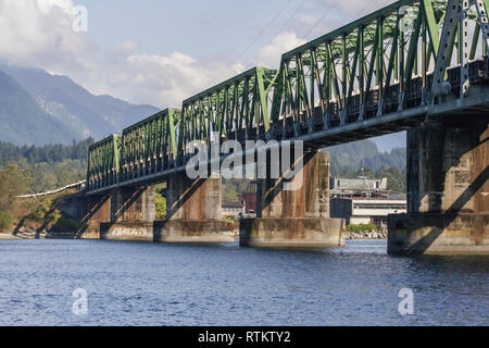 A water level view of a long line of train cars crossing Burrard Inlet on the Second Narrows Railway Bridge, moving from the North Shore to Vancouver. Stock Photo