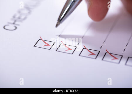 Close-up Of Person's Hand Marking On Checklist With Pen Stock Photo