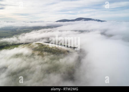 A cloud inversion over the Upper Clyde Valley in South Lanarkshire clearing to reveal Tinto Hill and Quathquan Law protruding above the mist. Stock Photo