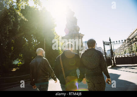 BARCELONA, SPAIN - NOV 12, 2017: Three young male friends walking to the exit of the Parc de la Ciutadella on a sunny day with beautiful natural sun flare  Stock Photo