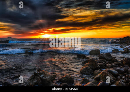 Bright sunset under the storm sea with waves splashes Stock Photo