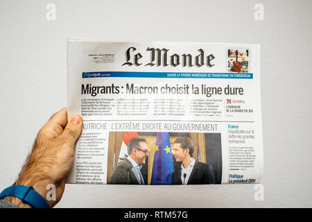PARIS, FRANCE - DEC 18, 2017: Man reading Le Monde French cover newspaper with headlight and picture about new Chancellor of Austria Sebastian Kurz and Heinz-Christian Strache Austria's vice chancellor Stock Photo
