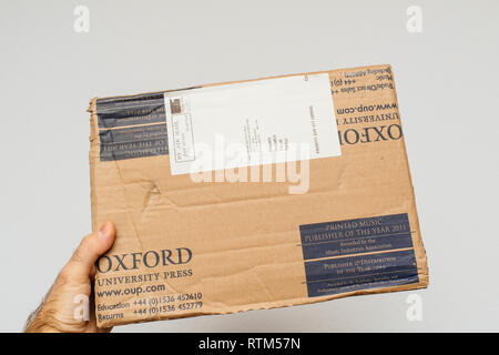 PARIS, FRANCE - DEC 18, 2017: Man holding Oxford Library Press cardboard parcel against white background  Stock Photo