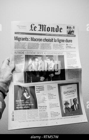 PARIS, FRANCE - DEC 18, 2017: Man reading Le Monde French cover newspaper with headlight and picture about new Chancellor of Austria Sebastian Kurz and Heinz-Christian Strache Austria's vice chancellor Stock Photo