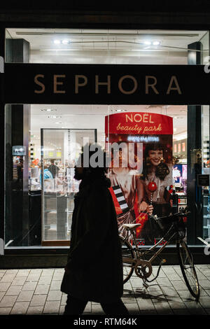 STRASBOURG, FRANCE - NOV 21, 2017: Male of black ethnicity passing by a bicycle parked in front of Christmas-decorated display windows of a Sephora perfume and cosmetics shop Stock Photo