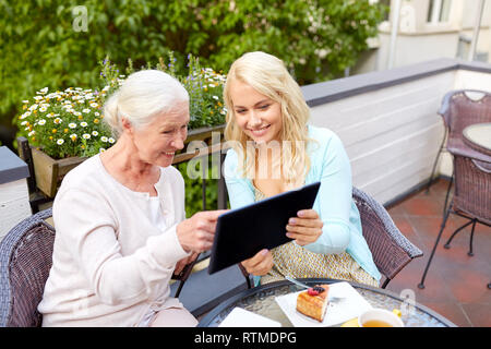 daughter with tablet pc and senior mother at cafe Stock Photo