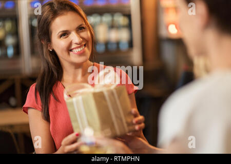 woman receiving present from friend at restaurant Stock Photo