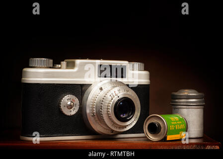 Horizontal close up shot of an old 1950’s 35mm camera and film on a brown background with copy space. Stock Photo